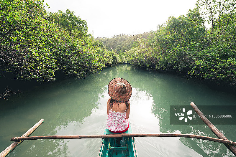 菲律宾，日落时分，一名女子在小船上探索河流图片素材