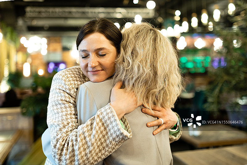 两个女性朋友在咖啡馆见面，拥抱在一起图片素材