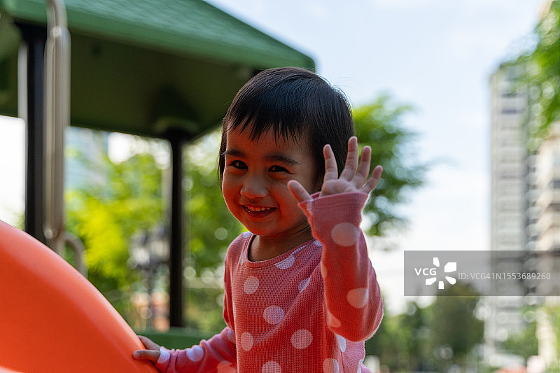 可爱的小亚洲女孩在玩的时候挥手图片素材
