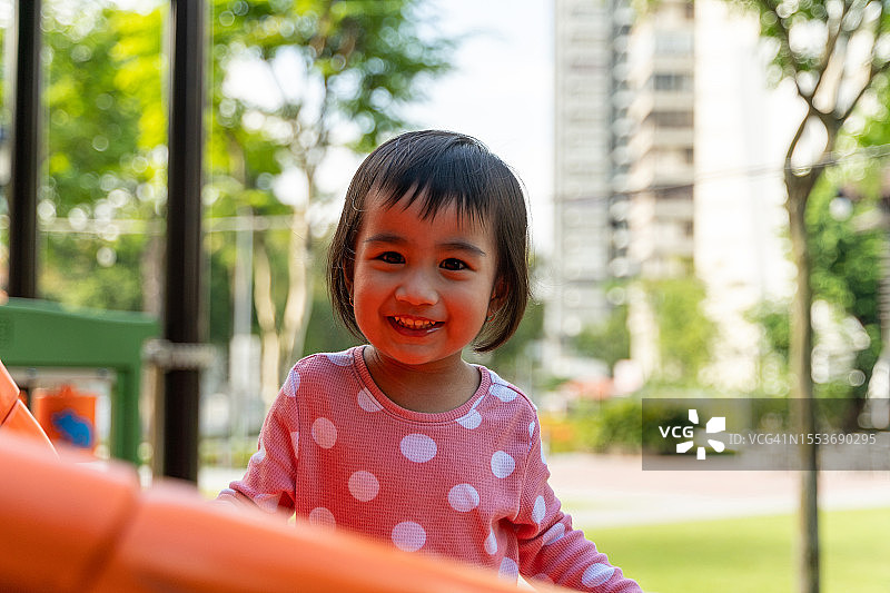 可爱的亚洲小女孩在城市公园的操场上玩耍图片素材