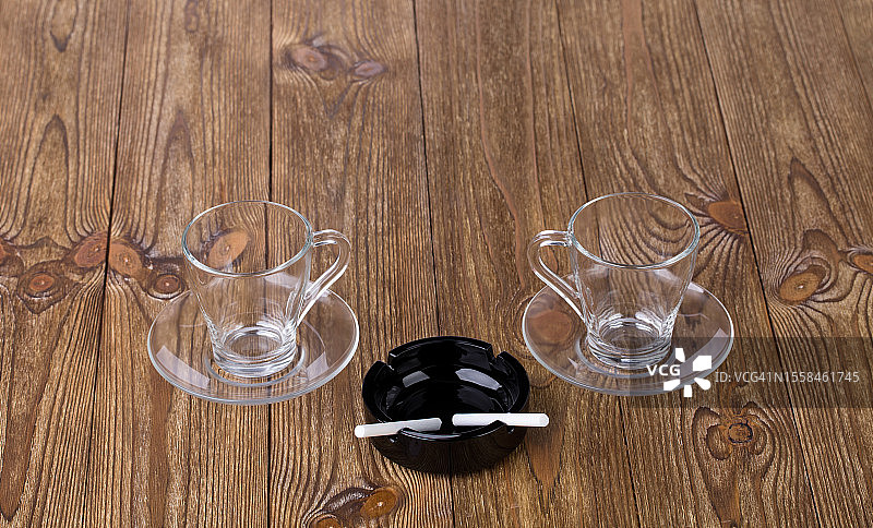 摩尔多瓦，木桌上的两个空杯子和黑色烟灰缸里的两根香烟图片素材