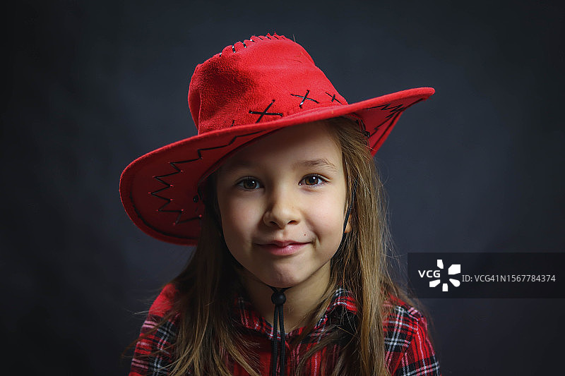 黑色背景下戴着帽子的微笑女孩肖像图片素材