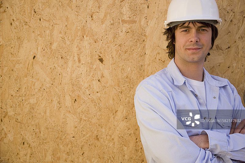 一个戴着安全帽的年轻人在建筑工地的肖像图片素材