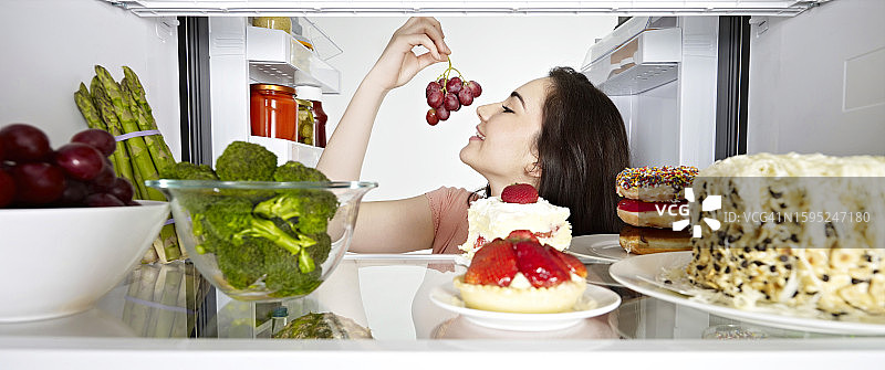 女人在吃冰箱里的葡萄图片素材