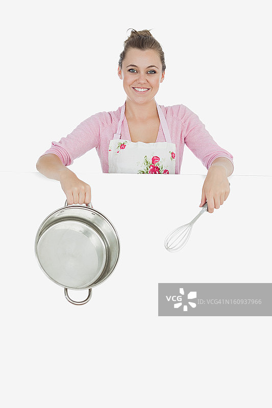 广告牌后面的女人拿着金属搅拌器和搅拌碗图片素材