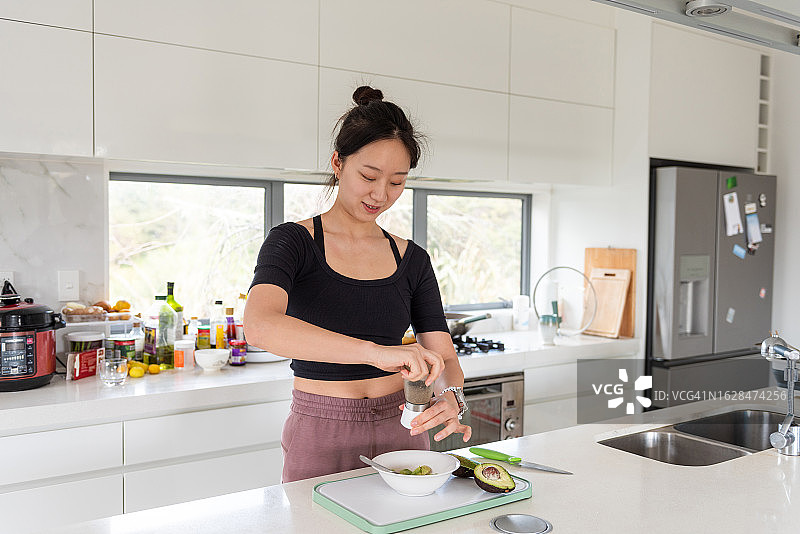 一个年轻的单身亚洲女孩在明亮的厨房里准备午餐图片素材
