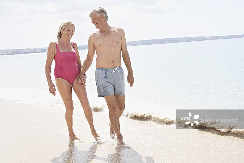 西班牙，马略卡岛，老年夫妇在海滩上散步图片素材
