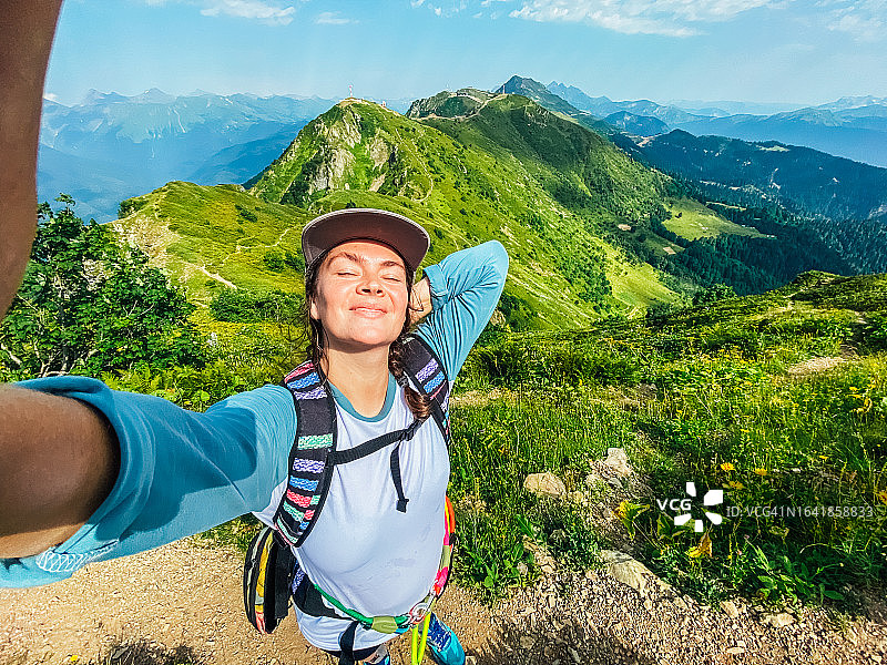 快乐的中年妇女在夏季徒步登山时拍下了一张令人惊叹的自拍照图片素材