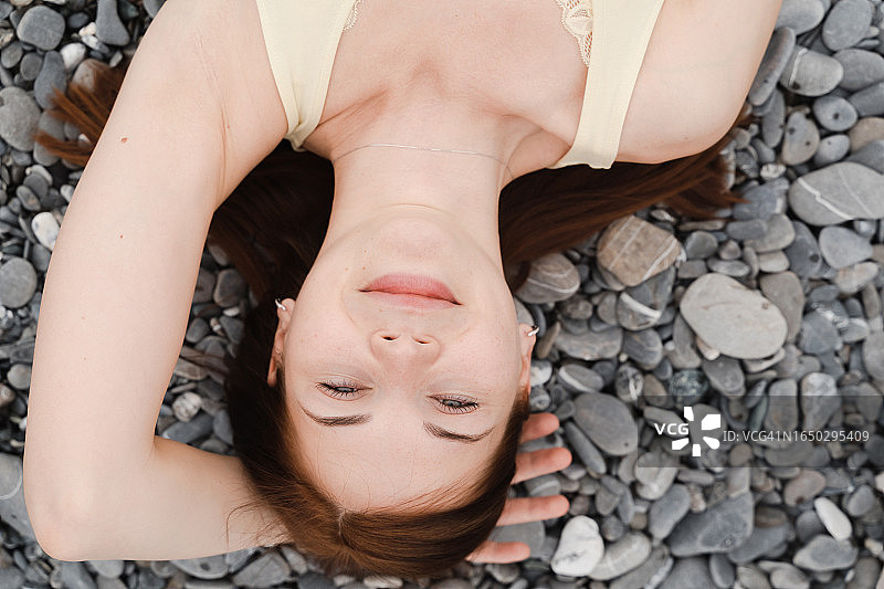 红发女人躺在卵石滩上放松图片素材