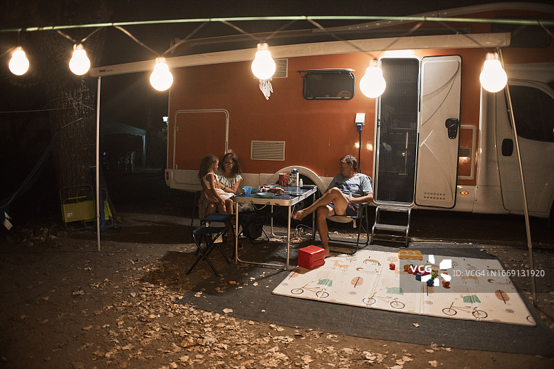 幸福的一家人在野外露营车旁的野餐桌旁聊天图片素材