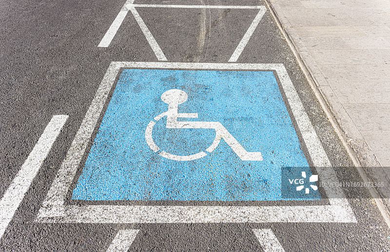 用蓝色漆在街上的残疾人停车标志。图片素材