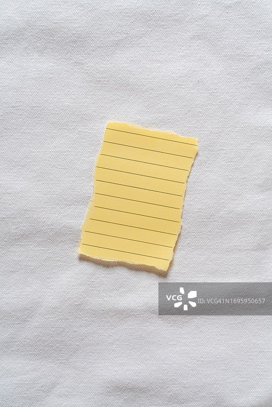 撕破的空白黄色便条纸贴在白布上图片素材