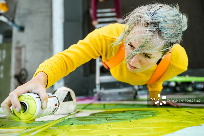 年轻的白人女性在屋顶上创作户外壁画图片素材