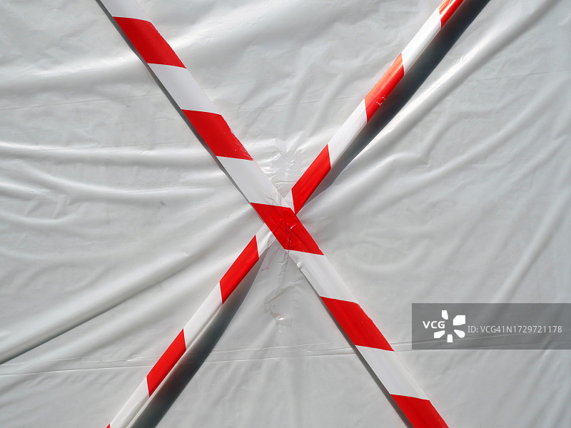 法国巴黎，红色和白色的警告带在白色塑料布覆盖的墙壁前交叉图片素材