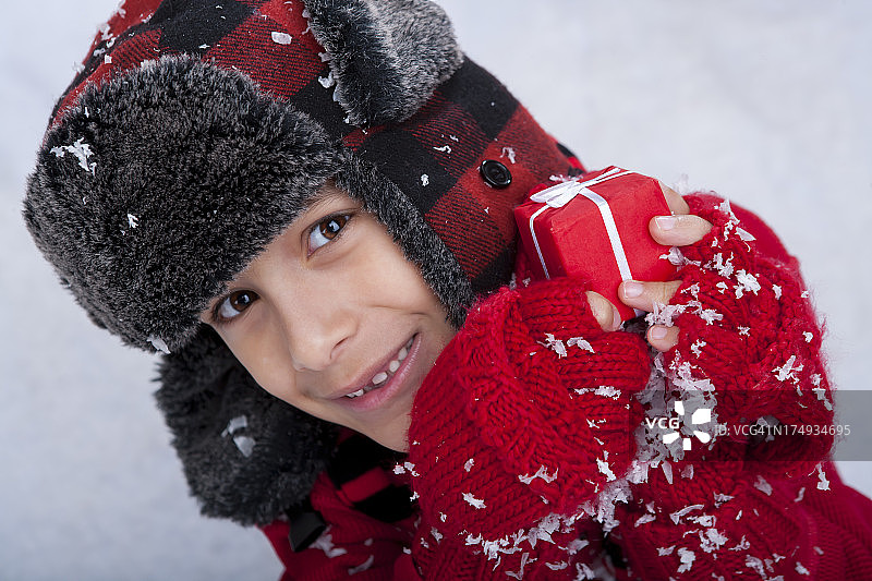 小男孩坐在雪地里拿着圣诞礼物图片素材