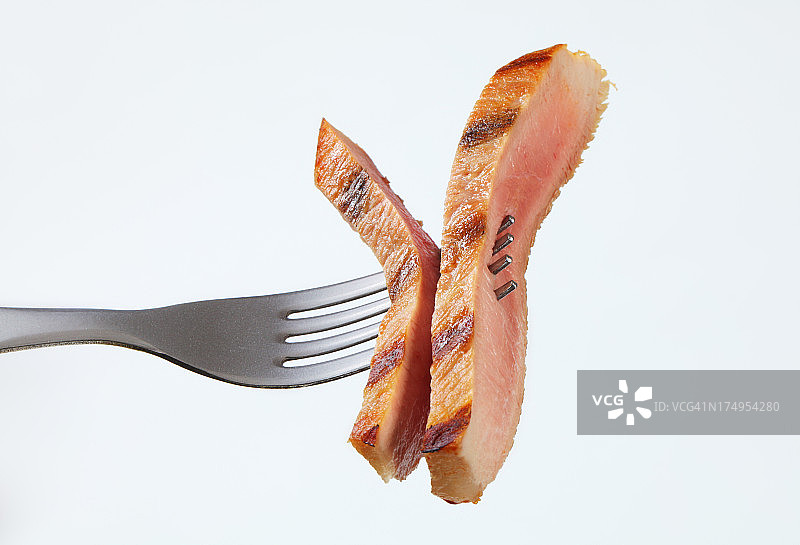 用叉子叉上半熟的猪肉片图片素材