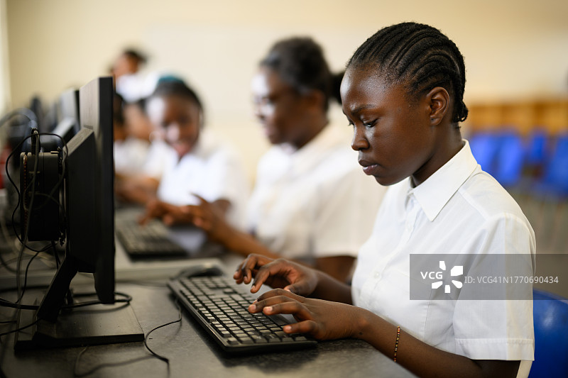 女学生一边在电脑上打字，一边聚精会神地看着键盘图片素材