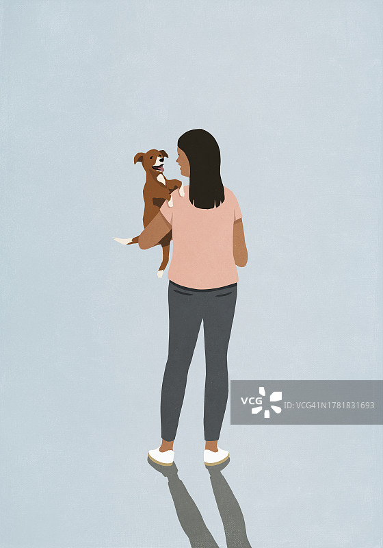 女人抱着蓝色背景的快乐小狗图片素材