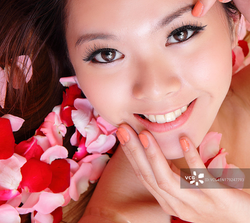 女孩微笑着，用红玫瑰触碰脸庞图片素材