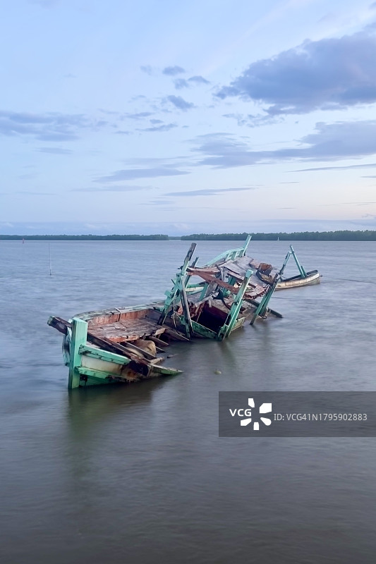 破碎的渔船在水中下沉。图片素材