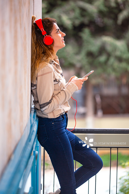 一个年轻漂亮的女人戴着耳机听音乐的画像。图片素材