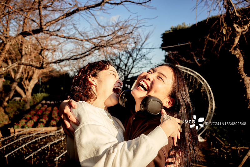 两个年轻女子互相拥抱笑着。图片素材