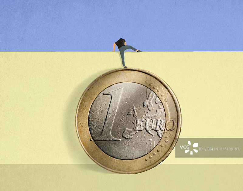 一名男子站在超大欧元硬币上翻墙图片素材