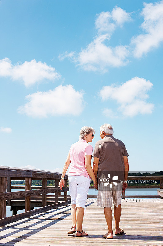一对老年夫妇在一个阳光明媚的日子里牵着手散步图片素材