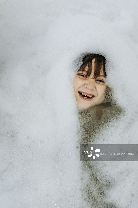 浴缸里沐浴着肥皂水的快乐男孩图片素材