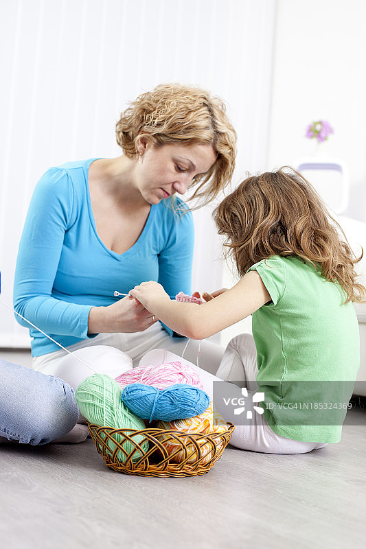 母亲和孩子在家里编织。图片素材