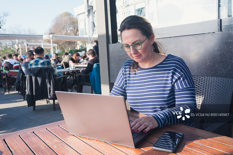 女性在户外咖啡馆上网，拥抱混合工作模式图片素材