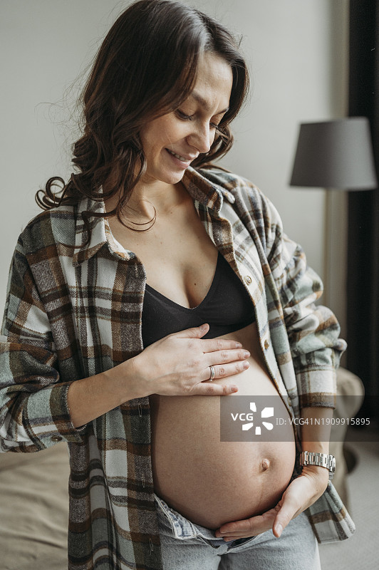 微笑的孕妇，双手放在肚子上图片素材