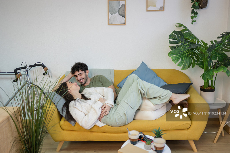 快乐的夫妇躺在沙发上拥抱图片素材