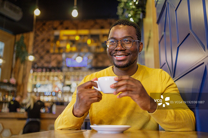 快乐的非裔美国人在咖啡馆里喝着早晨的咖啡图片素材