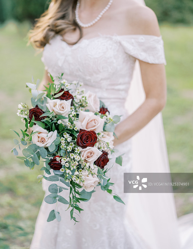 新娘手持花束站在户外的中间部分图片素材