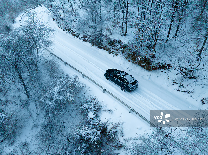 鸟瞰图，一辆汽车行驶在雪地上穿过森林图片素材