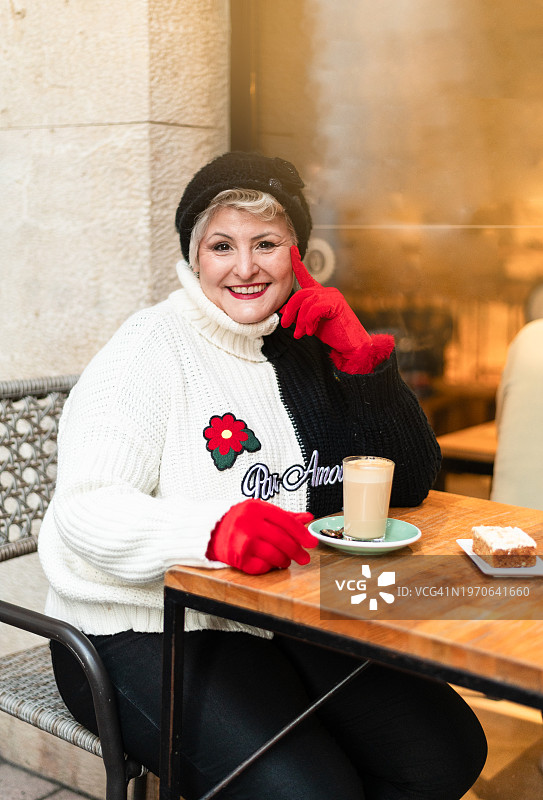 一个成熟的女人在户外自助餐厅喝咖啡图片素材