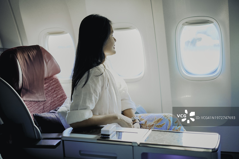一名商务舱乘客正放松地望着客机的窗外图片素材