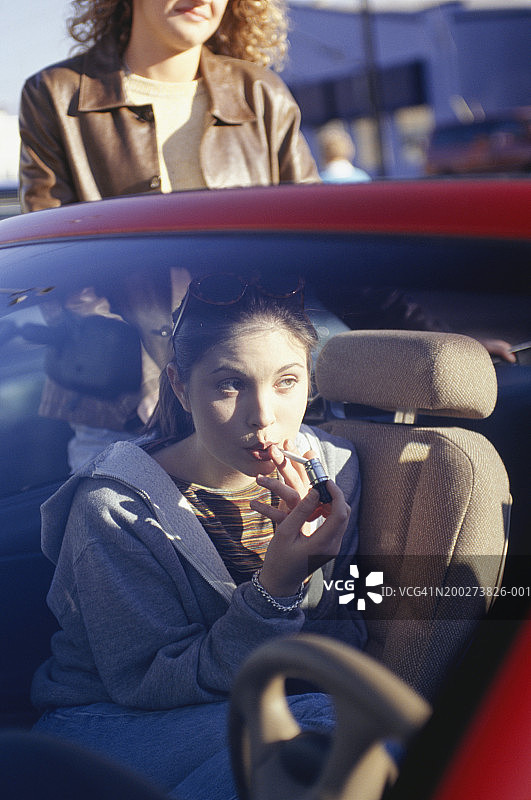 一名年轻女子在车里点燃香烟图片素材