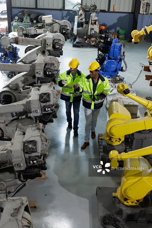 两名工程师在工厂一起检查机器人手臂图片素材