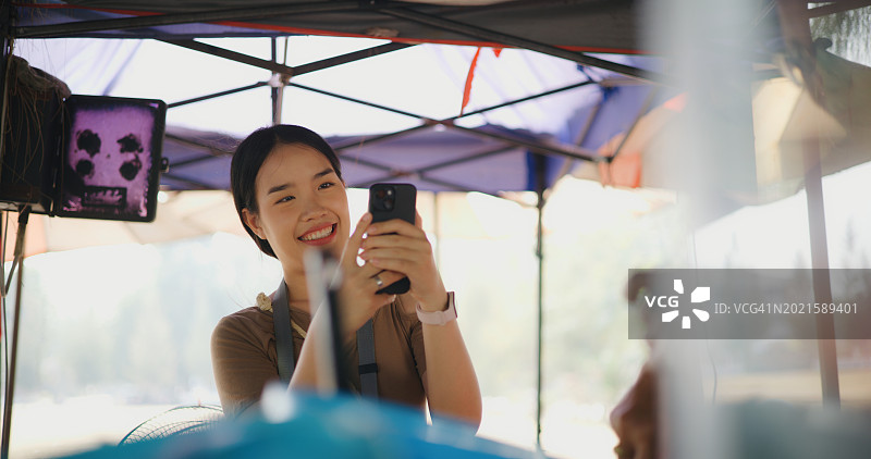 年轻的游客一边用智能手机给朋友拍照，一边做泰国菜沙拉图片素材