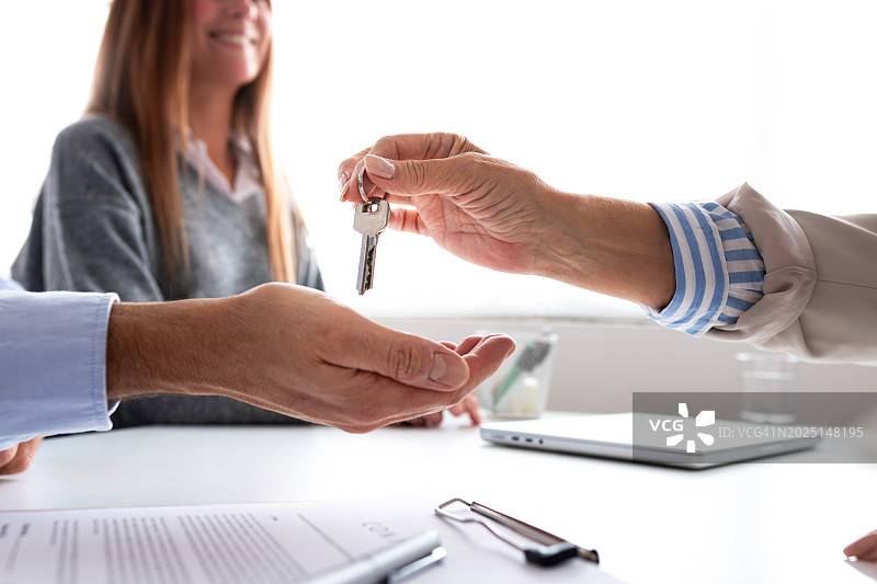 夫妻二人签订合同，共同购买第一套住房后，在房地产中介领取第一套公寓钥匙的特写。图片素材