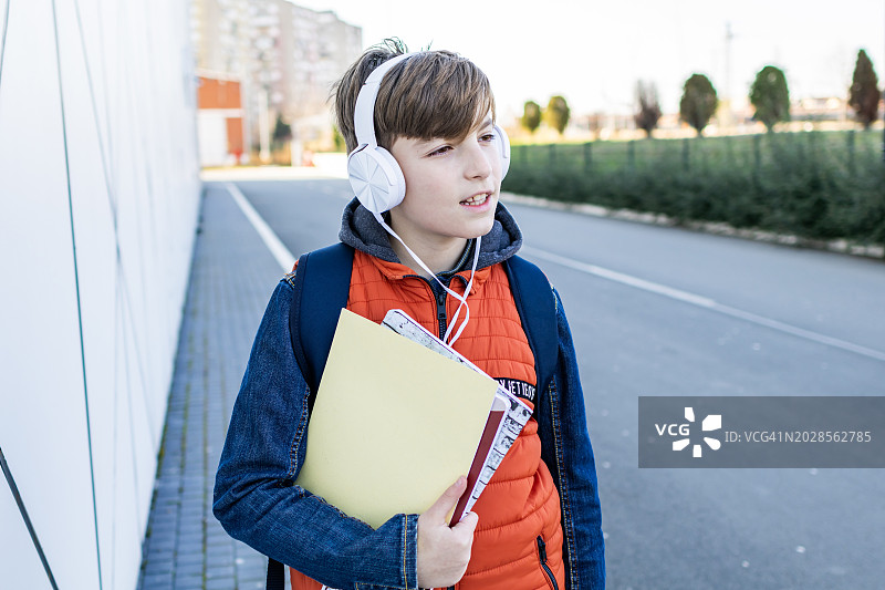 一个戴耳机的男生放学后要回家。图片素材