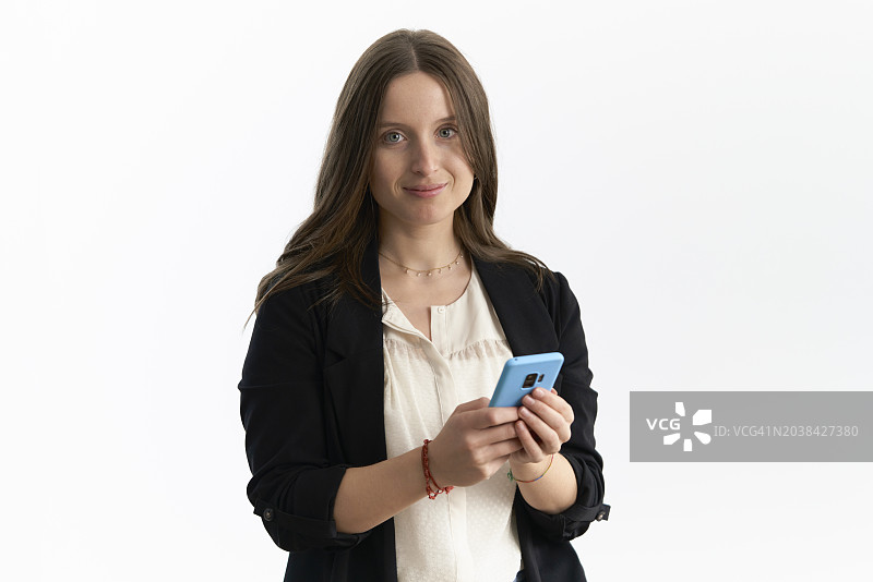 棕色头发的年轻职业女性在工作室用手机拍摄白色背景。图片素材
