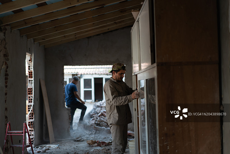 蓝领工人在一个房屋装修的建筑工地，看起来每个人都专注于他们的任务图片素材