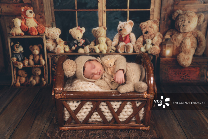 一个新生婴儿和泰迪熊一起睡在篮子里图片素材