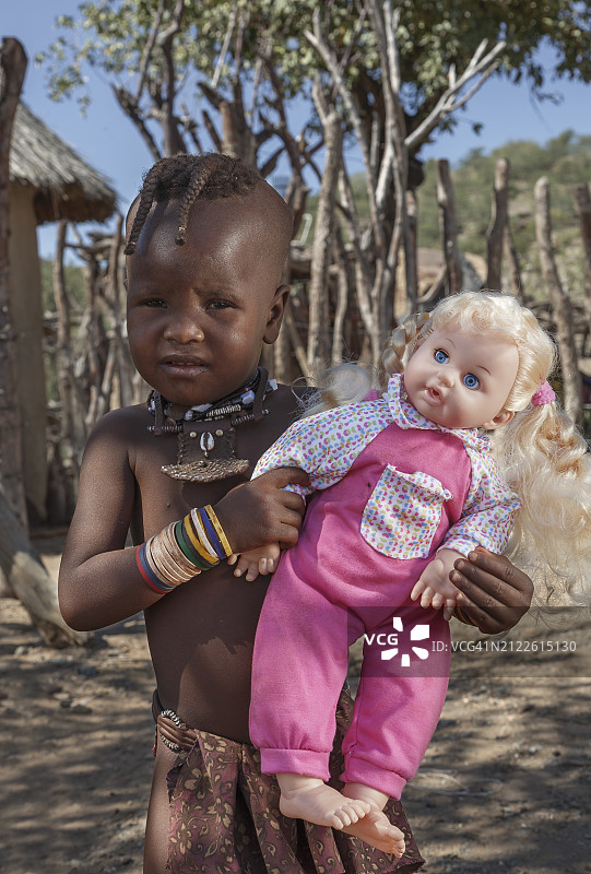 纳米比亚。抱着娃娃的辛巴女孩。图片素材