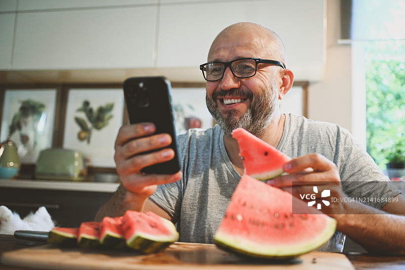 男子吃西瓜(带手机)图片素材