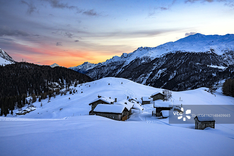 冬天日落时白雪覆盖的高山小屋图片素材