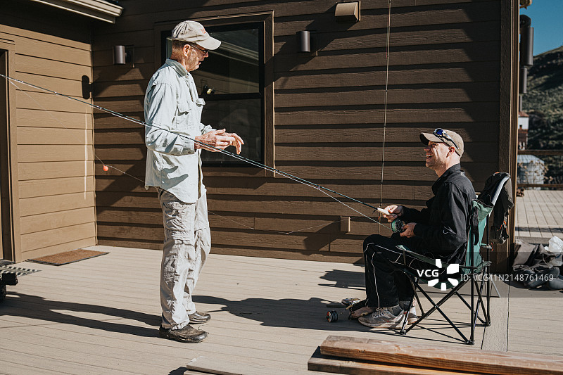 两个成熟的男性朋友准备在一个家的甲板上钓鱼图片素材